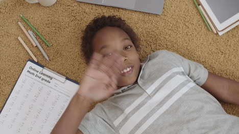 child laying on carpet doing online math homework