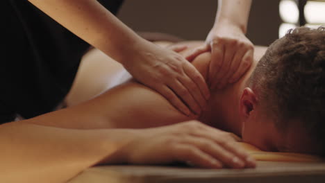adult man is relaxing in massage salon masseuse is kneading back muscles prevention and curing osteochondrosis