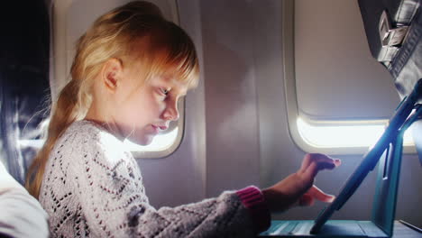 a girl enjoys the tablet in the aircraft