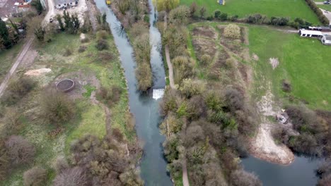a drone shot flying over the rural town of chartham, england following the stour river