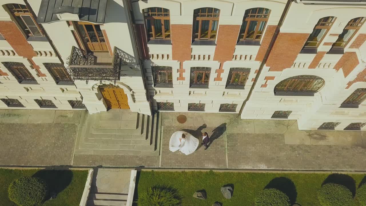 la novia gira en el novio por el edificio y el césped vista superior
