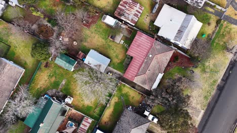 drone camera smoothly glides above suburban homes, gardens, and driveways in coonabarabran, new south wales, under natural daylight with steady overhead movement