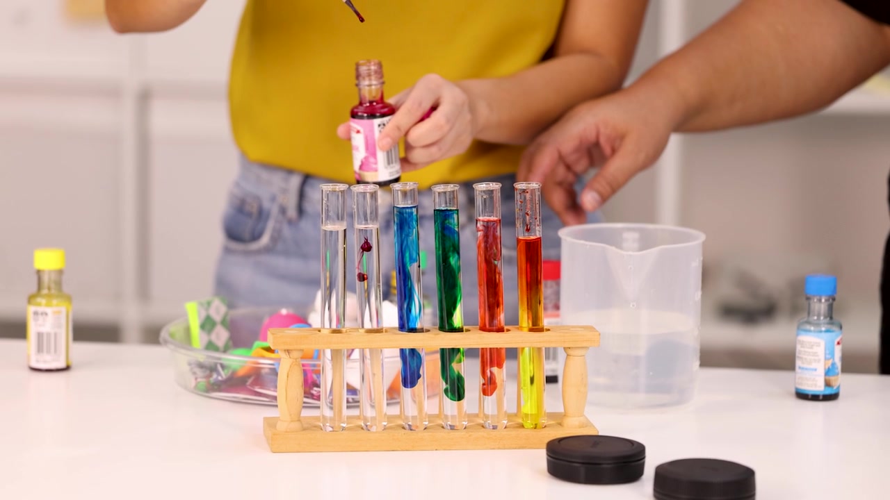 People Conducting Science Experiment with Colored Liquids in Test Tubes