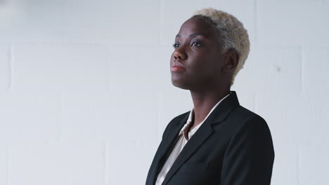 Portrait-Of-Determined-Young-Businesswoman-Wearing-Suit-Standing-Against-White-Studio-Wall