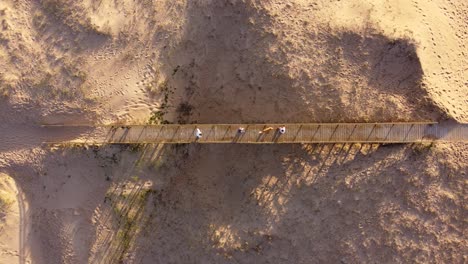 Gente-Con-Perro-Cruza-Un-Puente-De-Madera-A-La-Entrada-De-La-Playa-De-La-Ciudad-De-Punta-Del-Este-En-Uruguay-Al-Atardecer