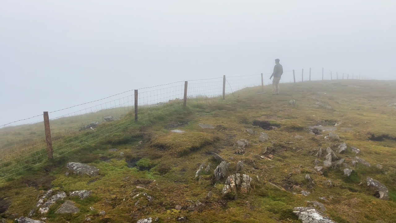 A mann walking in the mist - fog hill of the rural village in conor pass Ireland