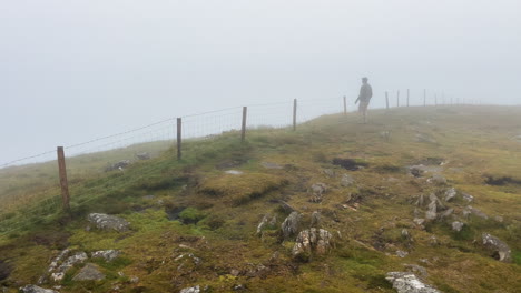 a mann walking in the mist - fog hill of the rural village in conor pass ireland