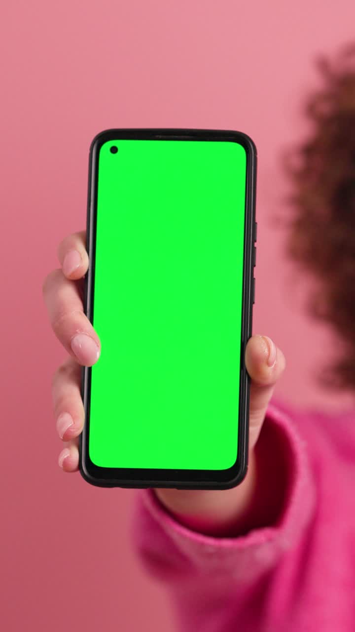 Happy woman showing mobile phone with chromakey in studio. Vertical footage