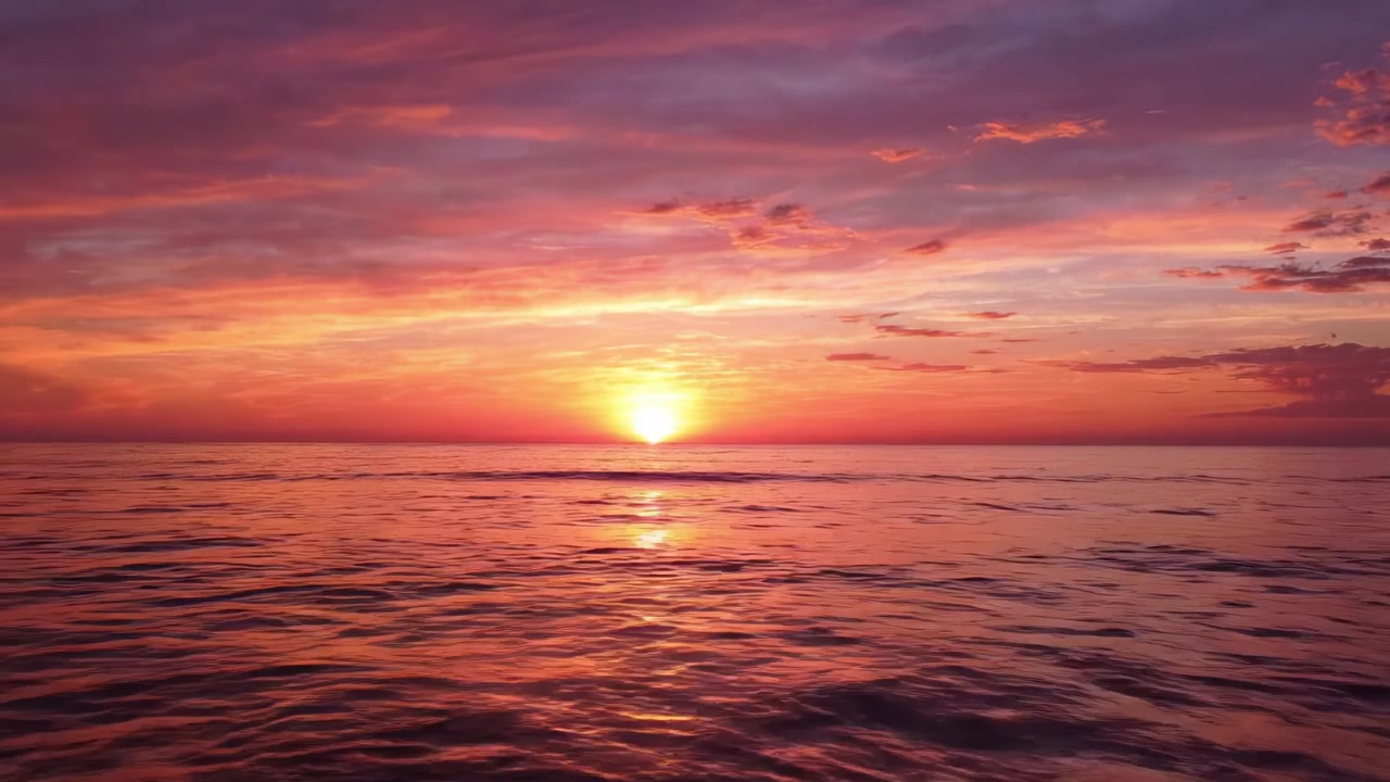 Pemandangan keindahan alam yang memukau saat matahari terbenam di atas samudra yang tenang, memancarkan rona cerah oranye, merah muda, dan ungu di langit yang damai saat senja.