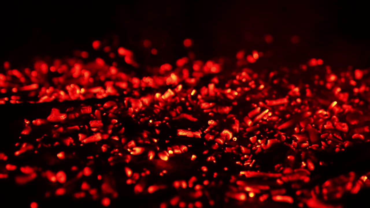 Pile of glowing charcoal after the campfire burnt out. Red pieces of burned wood still hot. Close up.