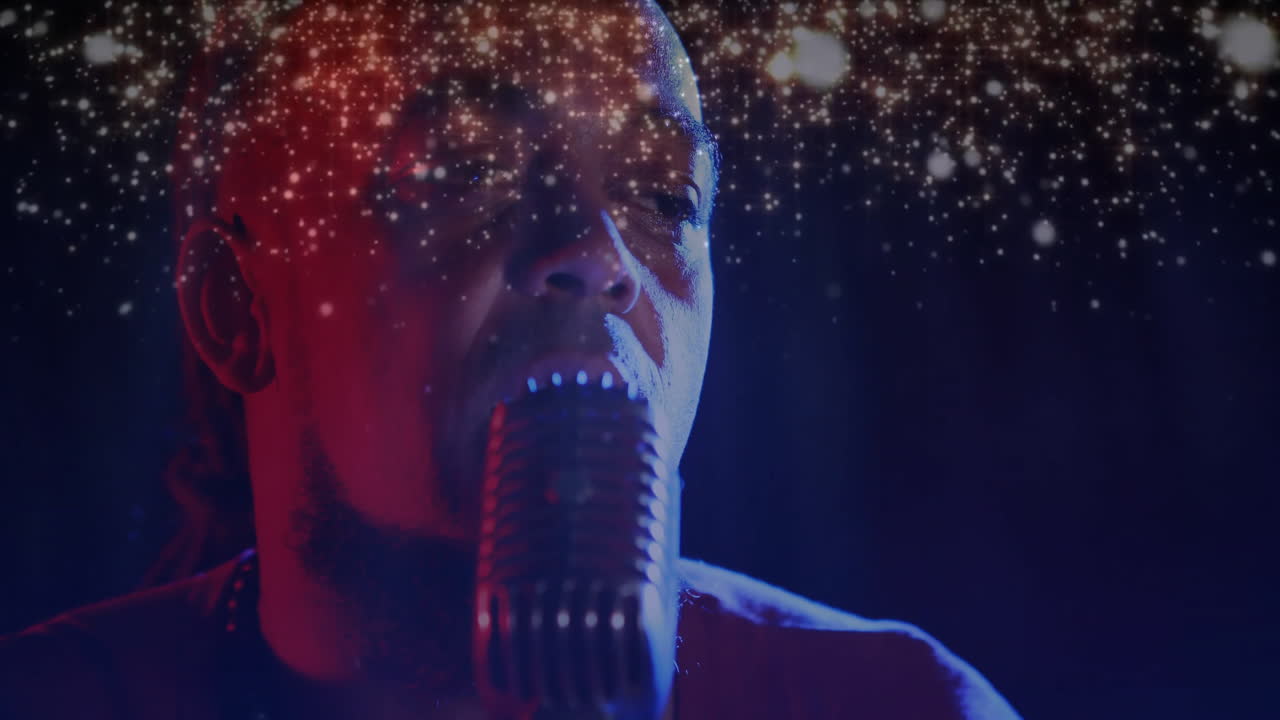 Male singer using microphone on stage, blending red blue lights with shimmering graphics for music