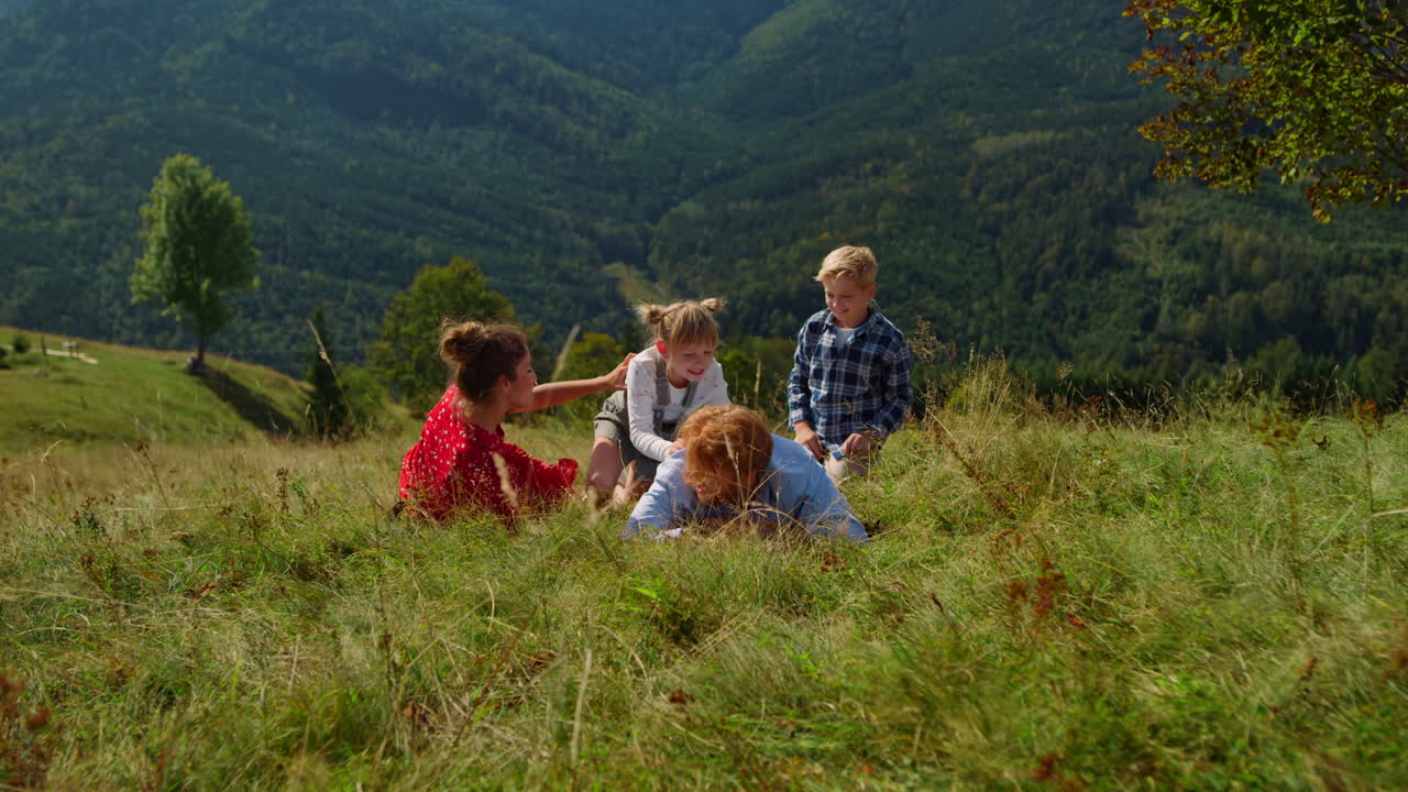 familia acostada en un prado verde en las vacaciones de verano. padres jugando con sus hijos.