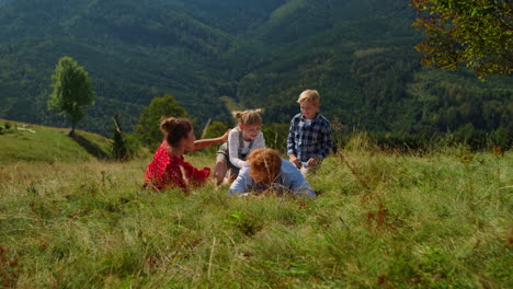 family lying ground green meadow on summer vacation. parents playing with kids.