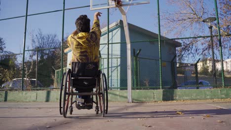 Disabled man playing basketball in a wheelchair, dribbling the ball.