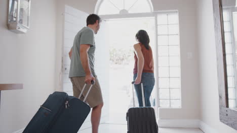 family with luggage opening front door and leaving for vacation