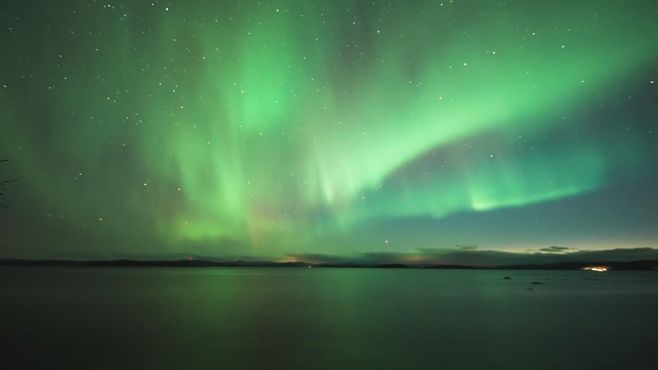 una danza hipnotizante de las luces del norte verdes y púrpuras en el cielo nocturno sobre las aguas oscuras del fiordo noruego.