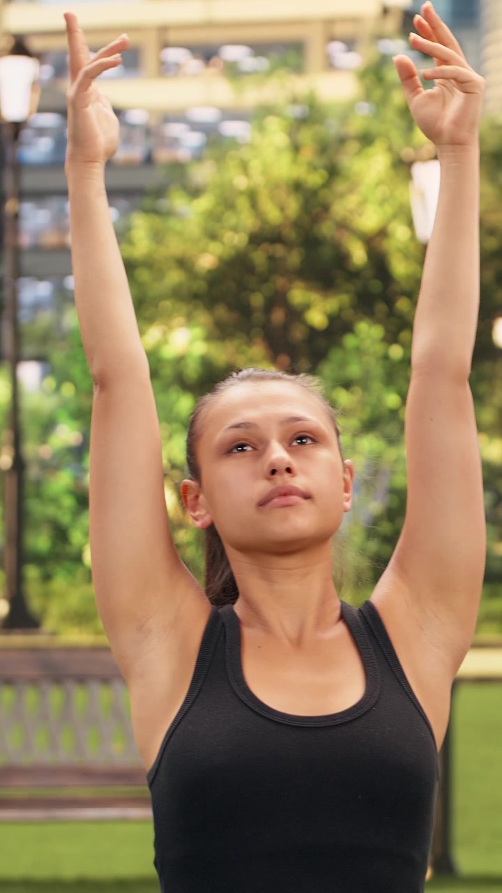 Video vertical de diversos participantes de yoga manteniendo posturas de guerrero sincronizadas con los brazos levantados