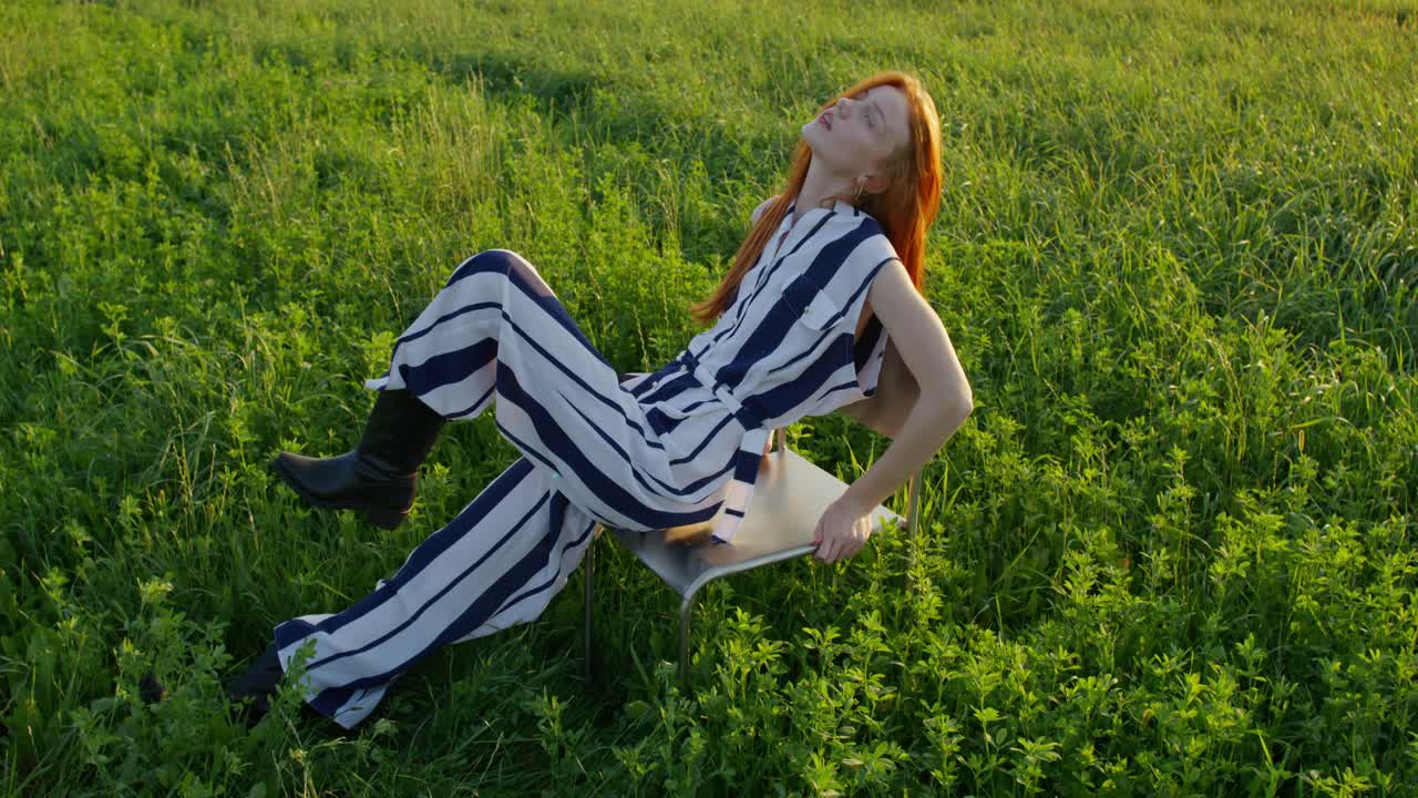 mujer en mono a rayas sentada en una silla de metal en un campo