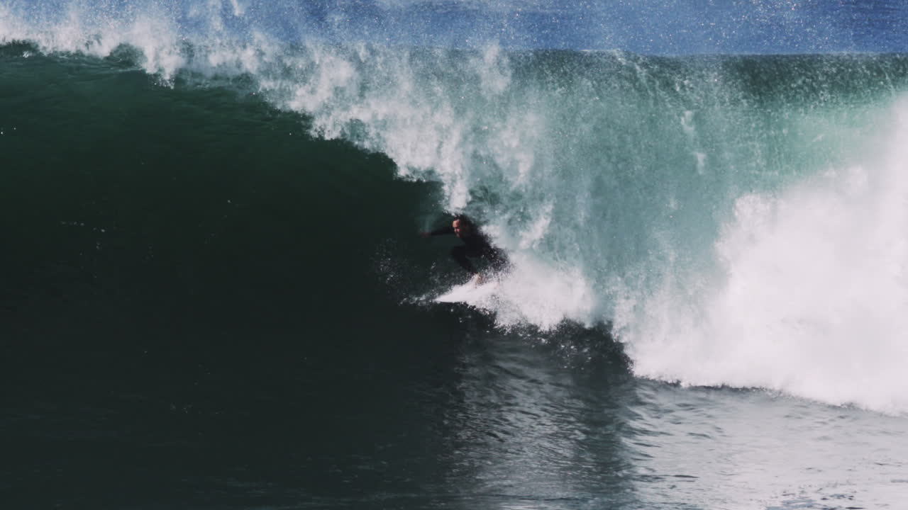 Low light surf barrel rolls over rider lit by foamy light glow from horizon behind