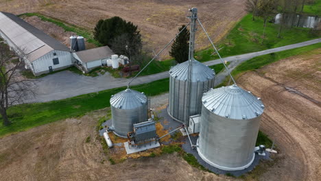 grain bins for corn storage on family farm with agriculture barn and chicken pig house in view