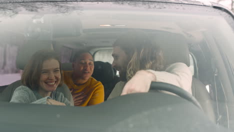 three happy friends talking and spending good time together while sitting in the car on a winter day