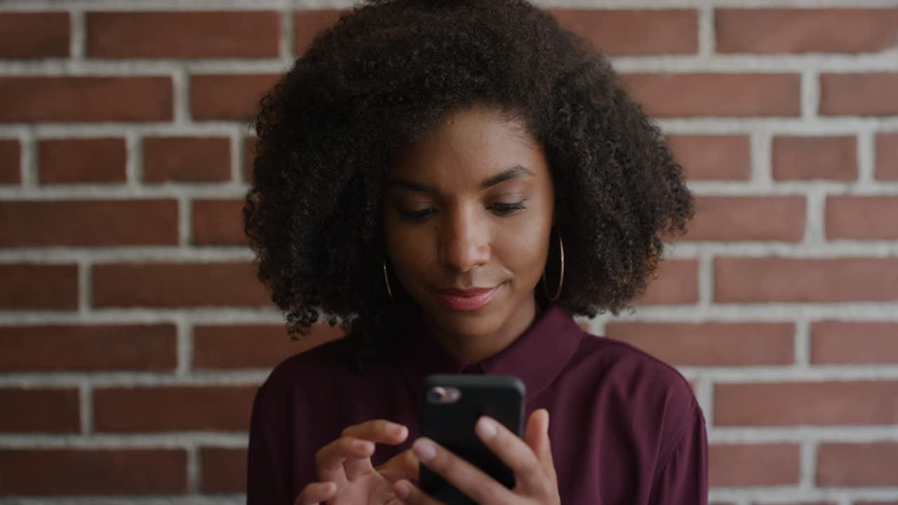 portrait stylish young african american woman using smartphone texting browsing messages online looking pensive black female trendy afro hairstyle technology connection