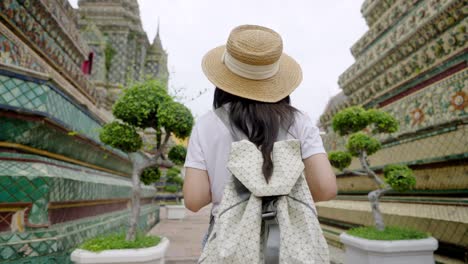 cheerful young asian woman traveling at wat pho temple in bangkok, thailand.
