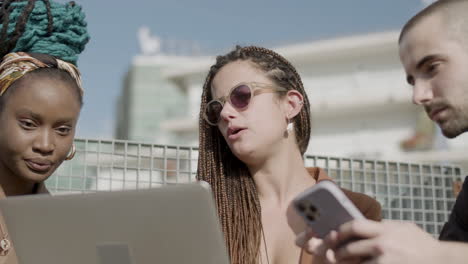 front view of girl showing coworkers her project on laptop