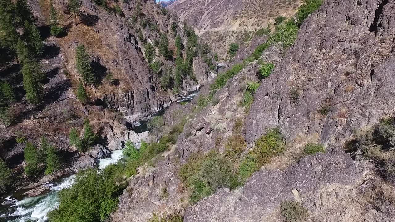 полет над крутым и изрезанным каньоном с рекой и водопадом внизу