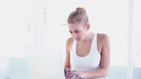 Sporty-smiling-blonde-using-laptop