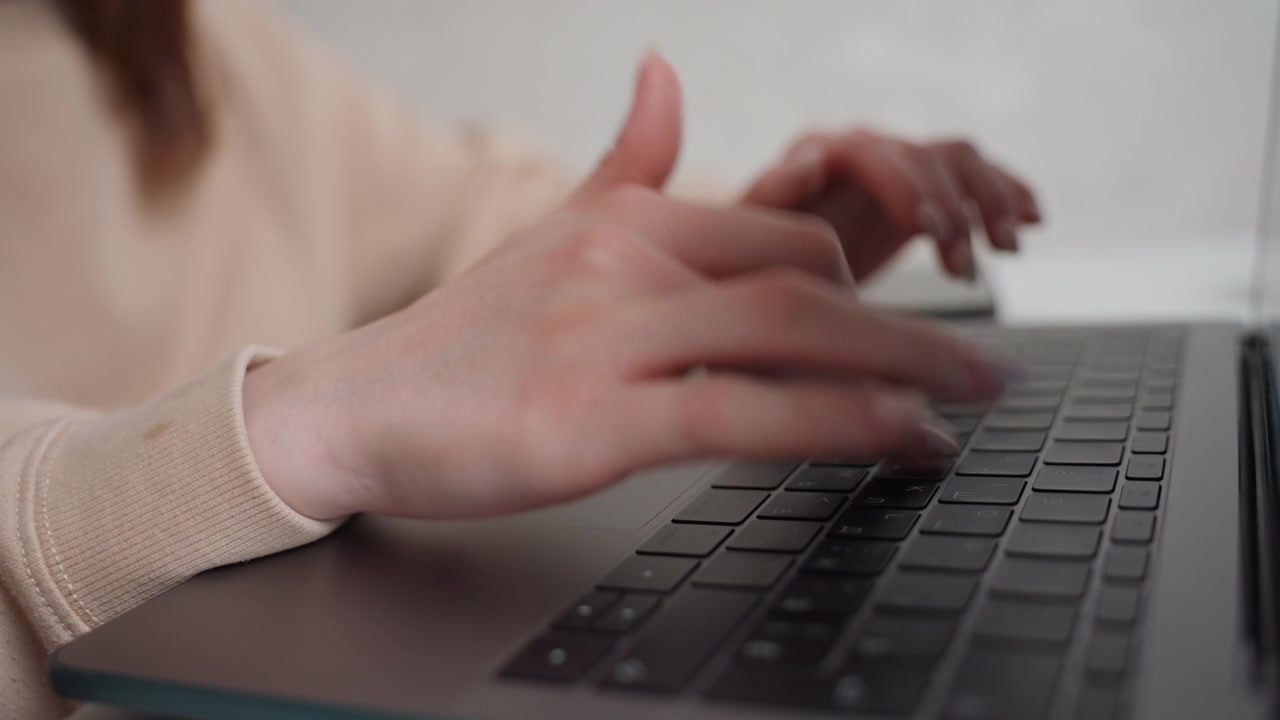 Primo piano di mani che lavorano al laptop a casa. Mani caucasiche che modificano attentamente la grammatica sul computer portatile. Primo piano di mani con un maglione morbido che si concentrano sulla modifica di compiti di grammatica educativa.