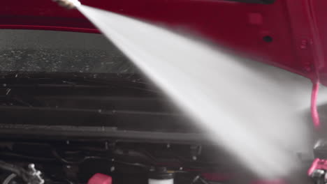 car wash: spraying water jet inside car hood engine