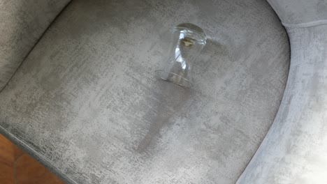 empty glass on a light gray fabric armchair