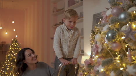 Junge-Und-Mädchen-Schmücken-Weihnachtsbaum-Mit-Kugeln-Und-Ornamenten,-Mutter-Hilft