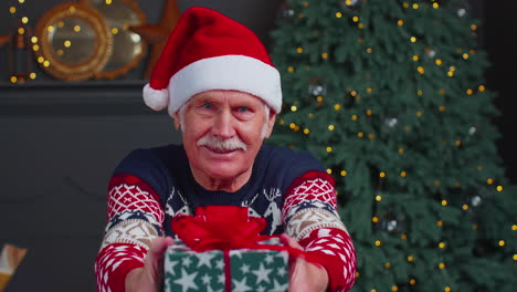 Abuelo-Mayor-Con-Suéter-Y-Sombrero-De-Año-Nuevo-Presentando-Caja-De-Regalo-De-Navidad,-Vacaciones-En-Casa