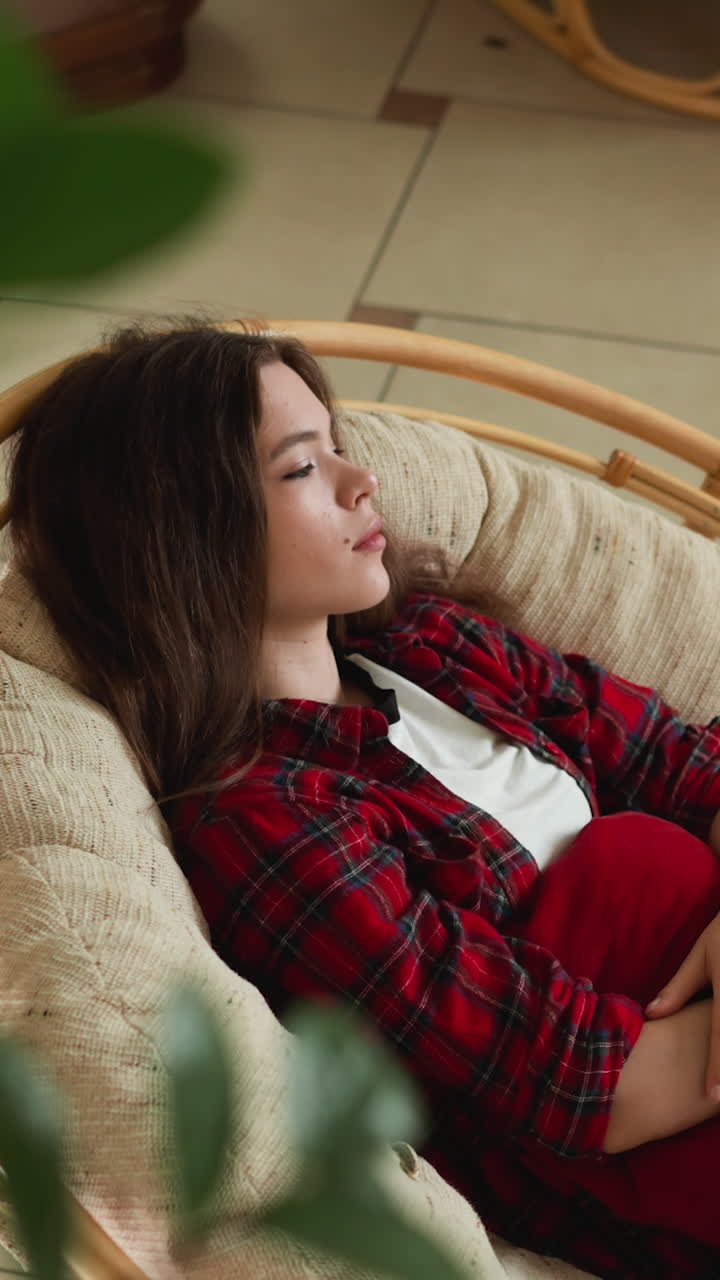 손에 베개를 들고 의자에 누워있는 여인은 기억에 사로잡힌 집의 조용한 구석들 사이에서 위안을 찾습니다.