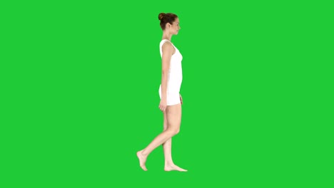 one female walking barefoot in white clothes on a green screen, chroma key