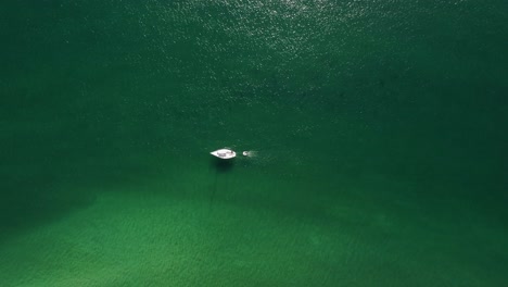 white sailboat sailing in the morning at a paradisiac crystal clear water