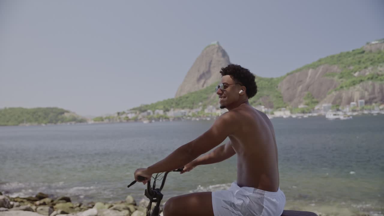 Uomo in bicicletta sul lungomare di Rio de Janeiro con il Pan di Zucchero sullo sfondo