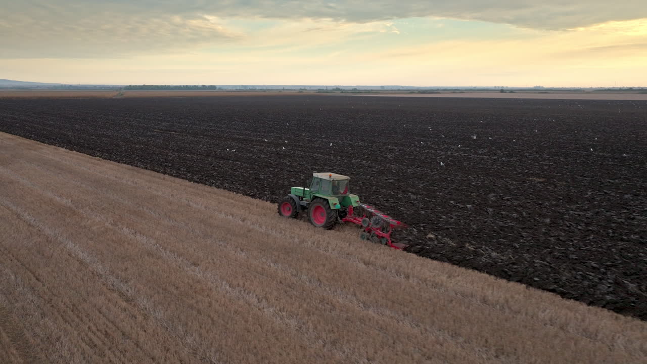 Tractor plowing field at sunset