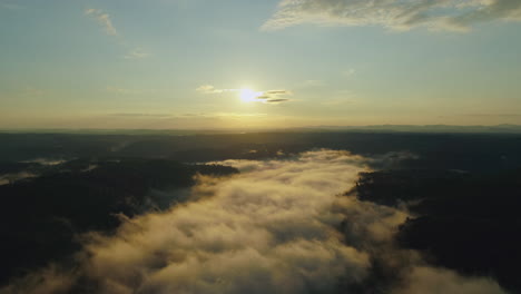 Aerial-sunrise-drone-shot-as-sun-burns-fog-from-away-from-forest-river-valley,-4K