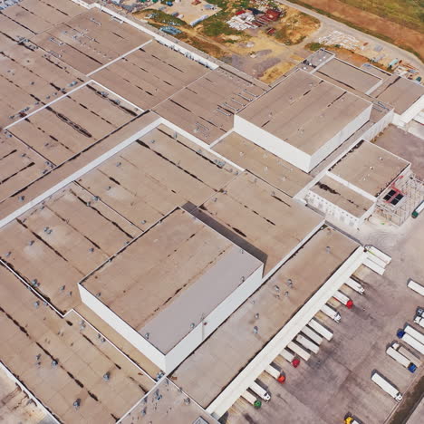 aerial shot of industrial warehouse/ storage building/ loading area where many trucks are loading/ unloading merchandise.