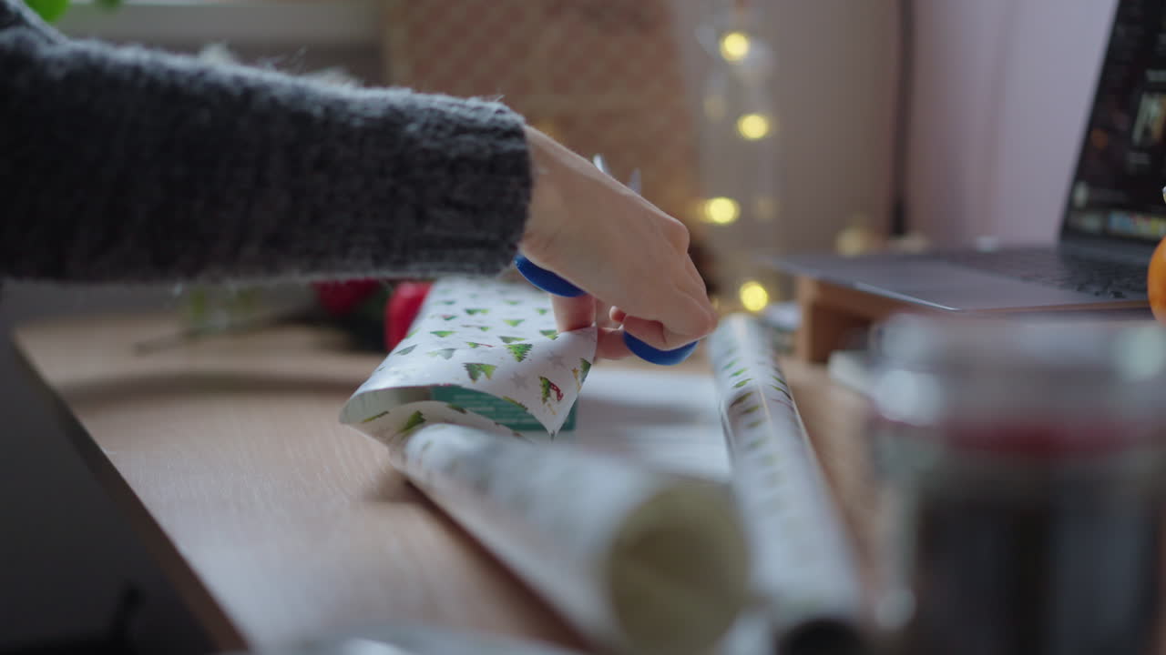 Close up of woman hands cutting wrapper sheet for packing gifts