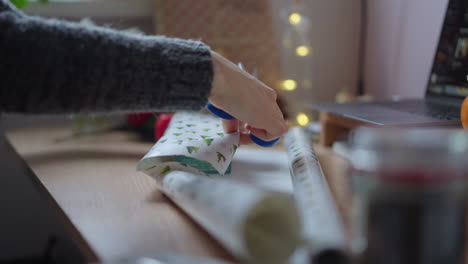 close up of woman hands cutting wrapper sheet for packing gifts