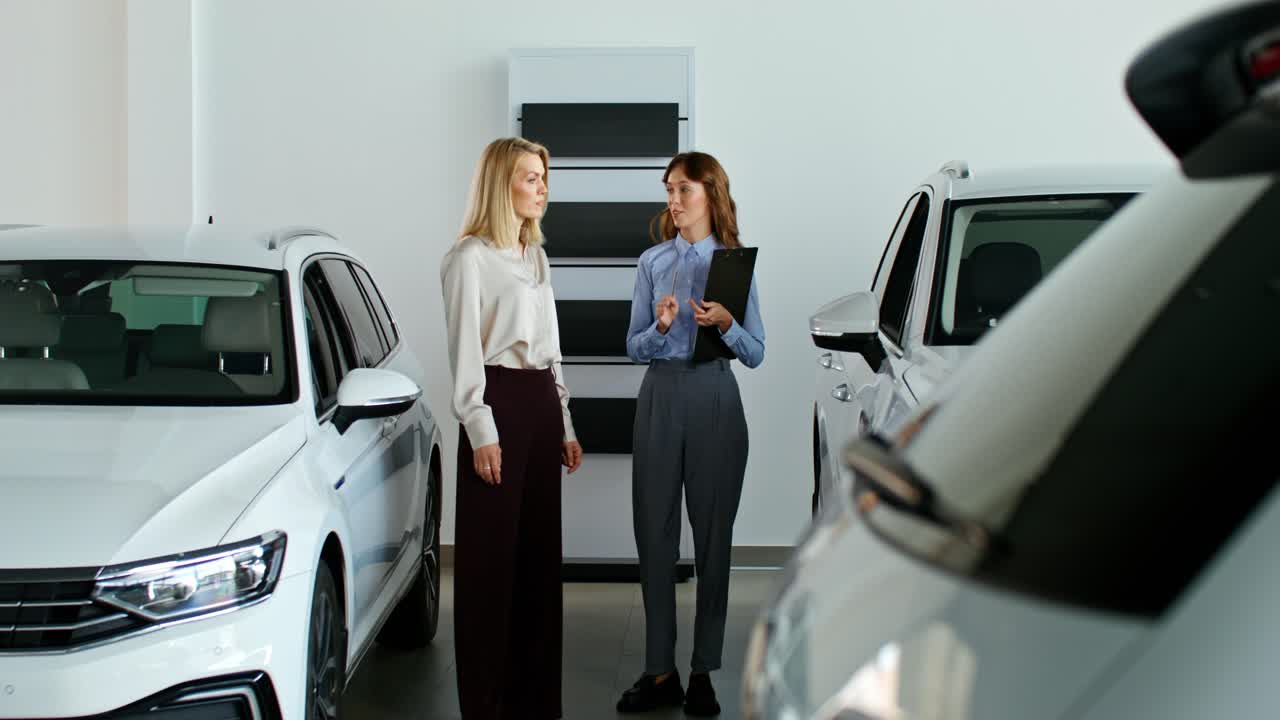 mujeres discutiendo coches en una sala de exposiciones