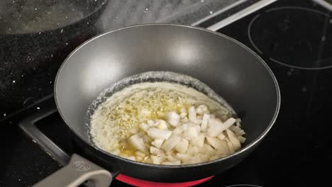 close-up of a frying pan while cooking onions in melted butter