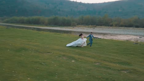 wedding couple running near mountain river. groom and bride. arial view