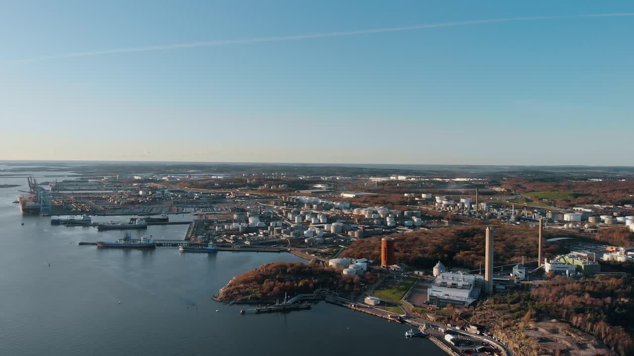 vista aérea de descenso lento por drones del área industrial en gotemburgo, suecia, con la reserva natural del bosque de rya visible en la parte inferior derecha detrás de la chimenea