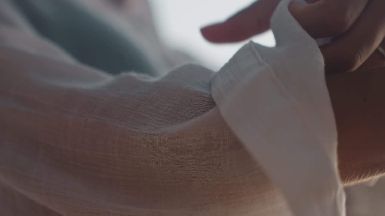 Mano che sistema un braccialetto. Primo piano di una mano che sistema un polsino con un accessorio turchese brillante al crepuscolo. Un individuo sistema il polsino e il braccialetto mentre si prepara per la sera sotto la calda luce del sole