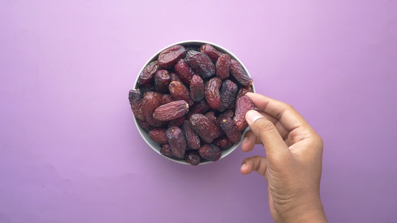 Hand pick a dried date fruit from a bowl